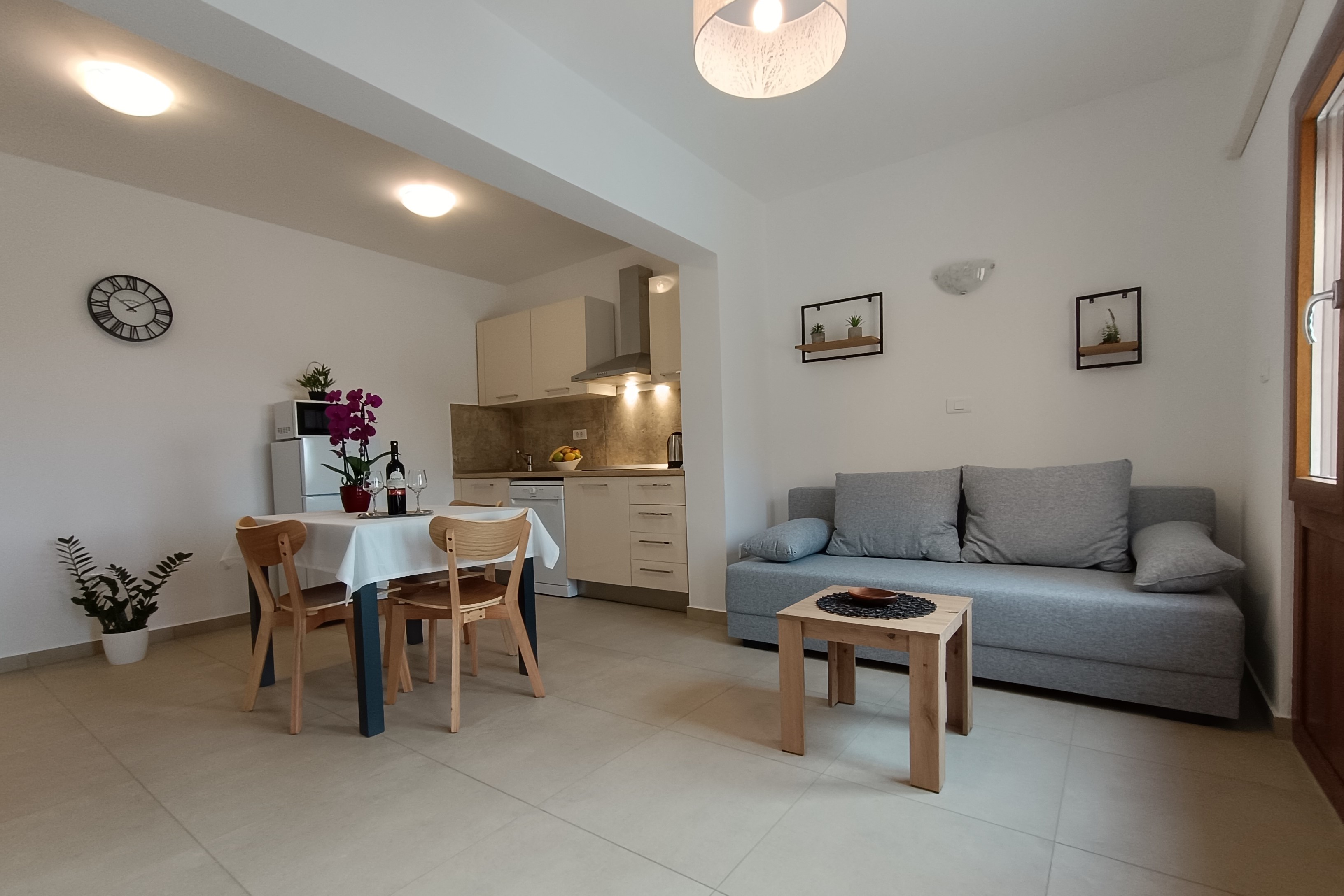 Beautiful colorful sunny garden, spacious parking space and a tiled access path. Colorful flowers filling the garden. A covered terrace and pergola in front of the apartment's entrance . Olive grove and nature in the background.